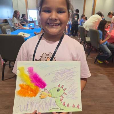 An art camp kiddo proudly displaying her art!